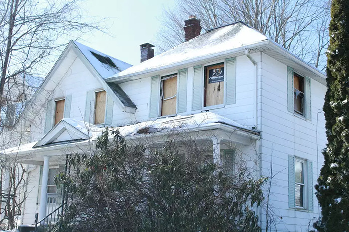 Abandoned house with boarded windows in winter, related to a man's story of captivity by stepmom.