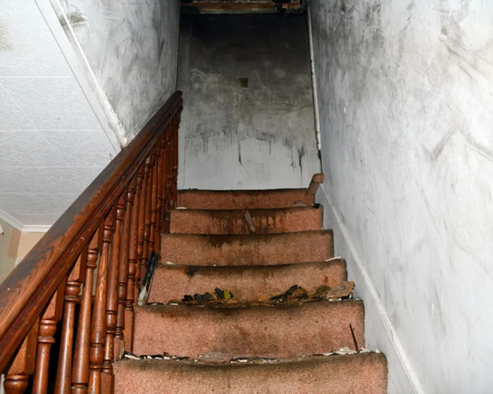 Dilapidated staircase in a gloomy, neglected house, symbolizing captivity and hardship faced by man for 20 years.