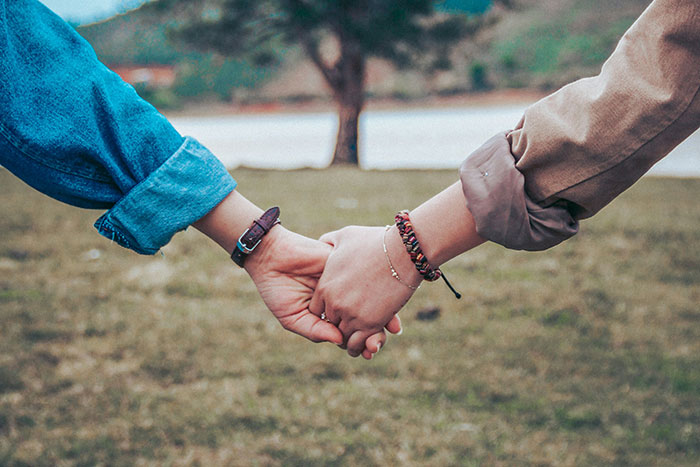 Two people holding hands outdoors, symbolizing being present and lessons men learned from their partners.