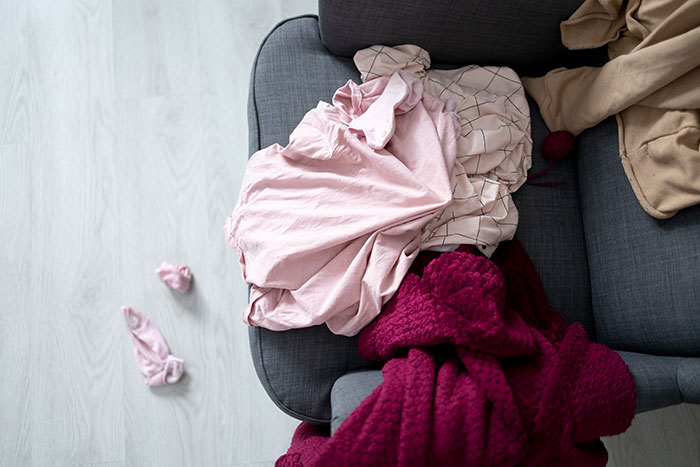 Cluttered couch with clothes and blankets scattered, illustrating the importance of being present in everyday moments.