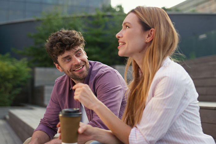 Man and woman talking outdoors, enjoying coffee and practicing being present during a meaningful conversation.