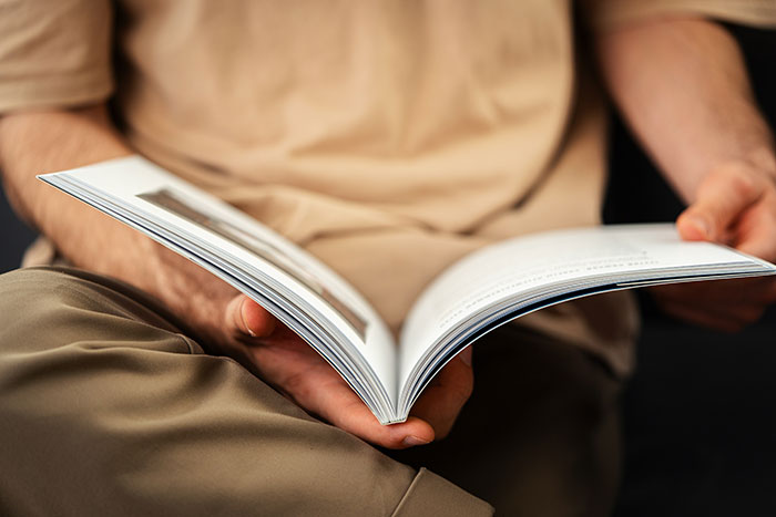 A young man holds an open book in a relaxed environment, related to bookstore age policy.