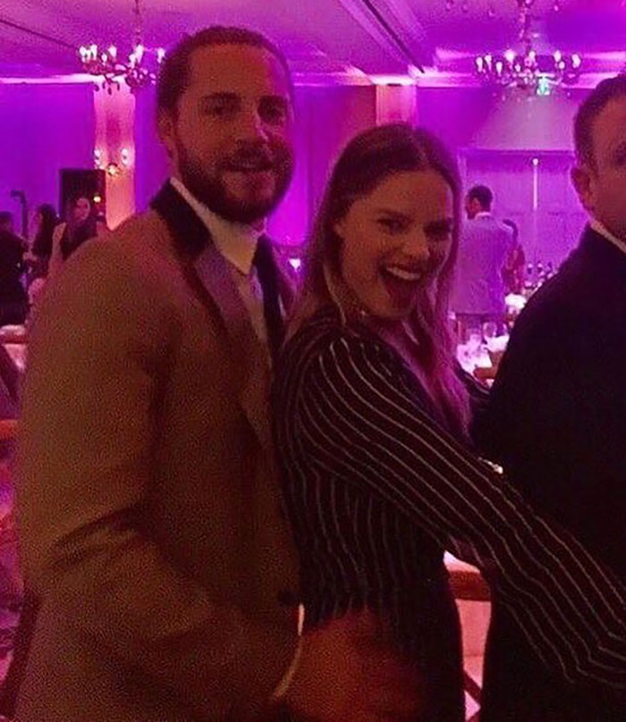 A woman in a striped outfit at a vibrant party, showcasing her postpartum body with confidence.