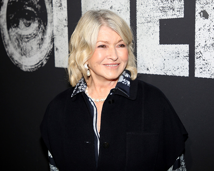 Martha Stewart smiling at an event, wearing a dark coat and light blouse, referencing Blue Origin astronauts in light humor.