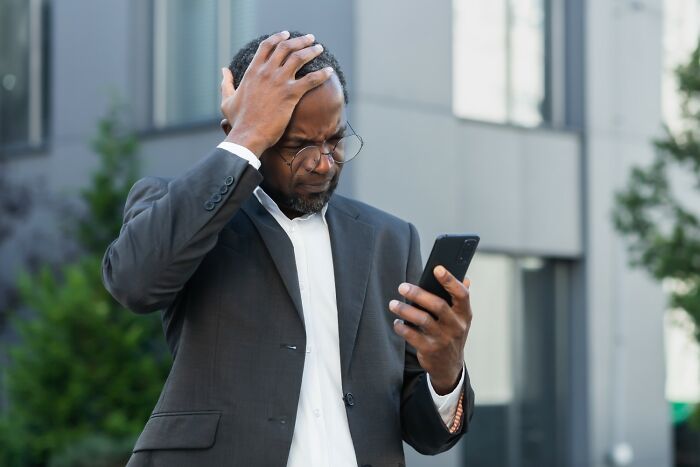 Man in a suit looking frustrated at his phone, pondering infamous traitors and back-stabbers from history.
