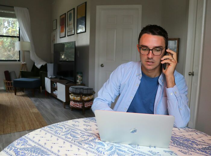 Man in blue shirt on laptop, discussing loopholes, seated at a table in a modern living room.