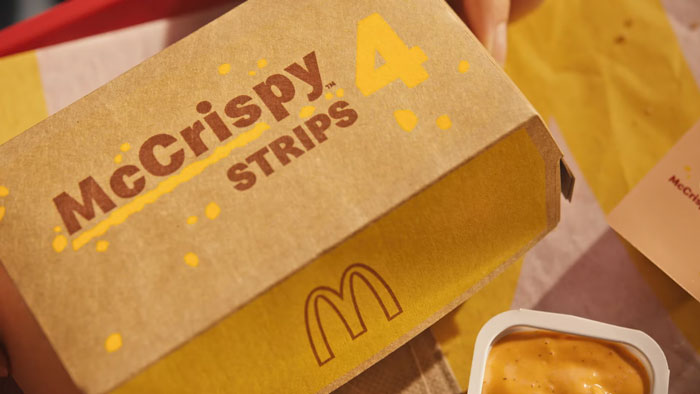 McDonald's McCrispy Chicken Strips box with sauce, highlighting their return.