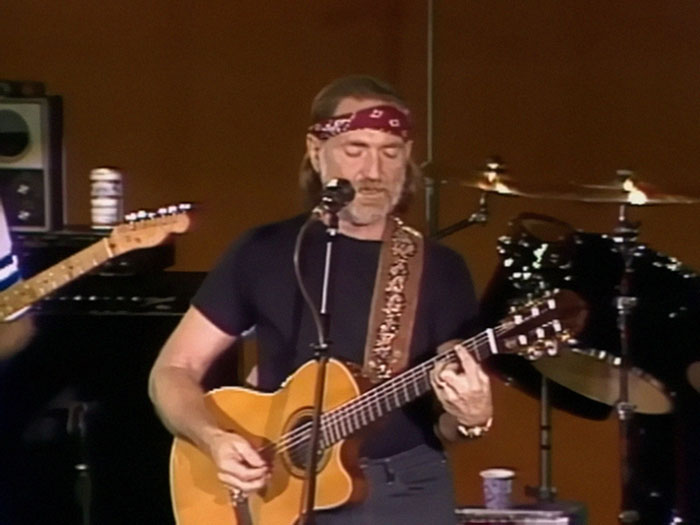 Musician performing on stage with a guitar and red bandana, part of celebrity encounters discussion.