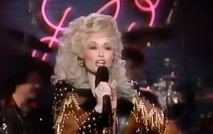 A celebrity performing on stage, displaying an unforgettable encounter in a dazzling outfit with a microphone.