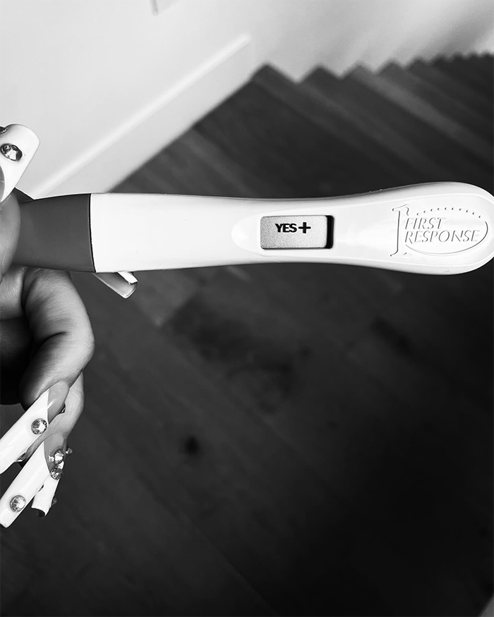 Positive pregnancy test held by person with long nails, related to Machine Gun Kelly and Megan Fox baby name confusion.