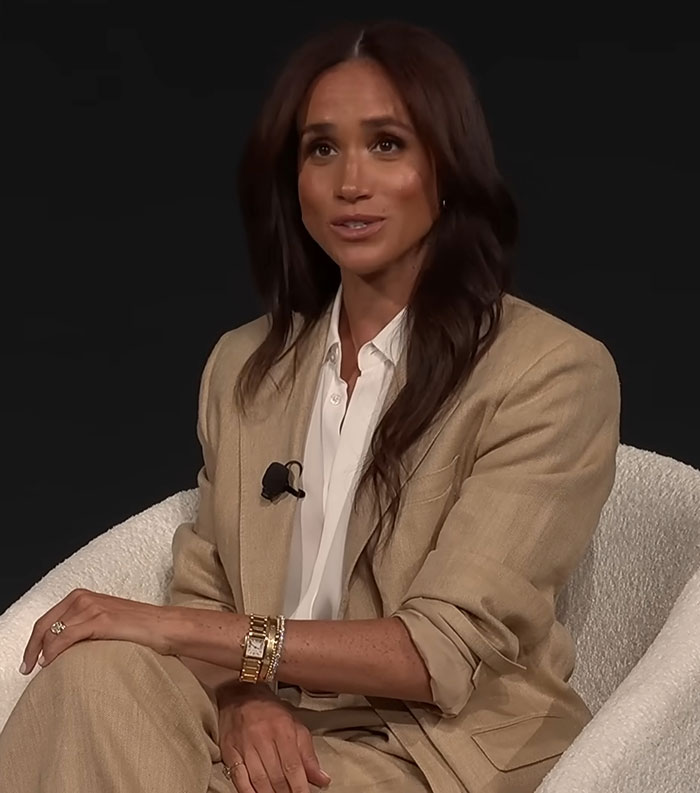 Meghan Markle in beige suit, seated with a microphone, discussing family photos of Lilibet and Archie.