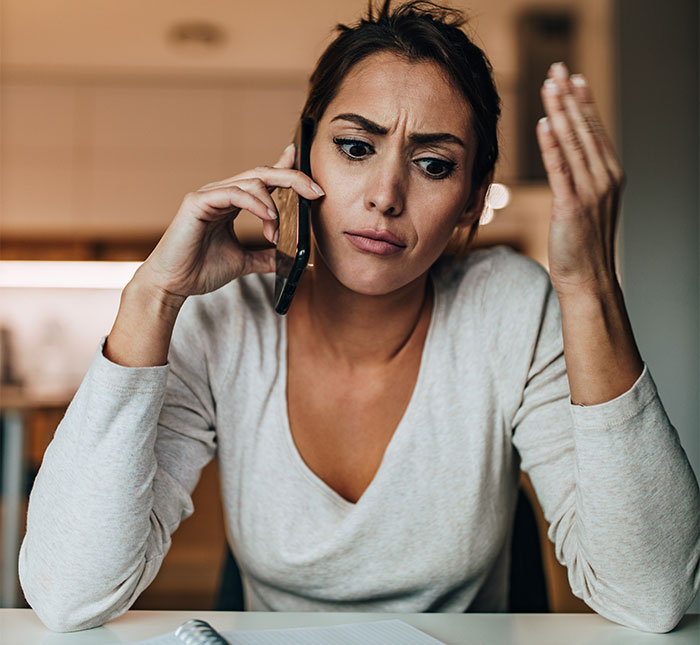 Woman on phone looking frustrated about wedding menu mishap.