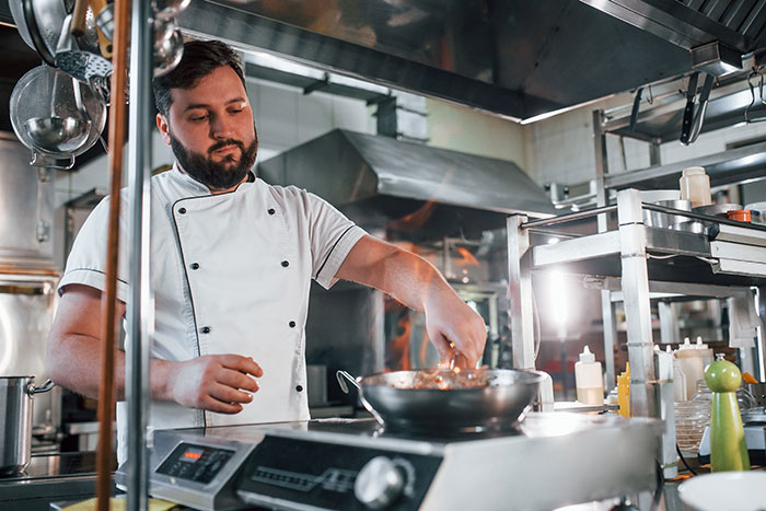 Chef in a kitchen preparing a dish, illustrating a lesson on "Password Protect Everything" for a wedding menu.