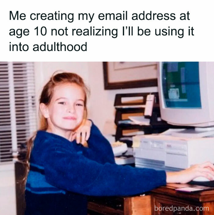 Young girl at a vintage computer creating an email, embodying millennial misery humor with an amused expression.