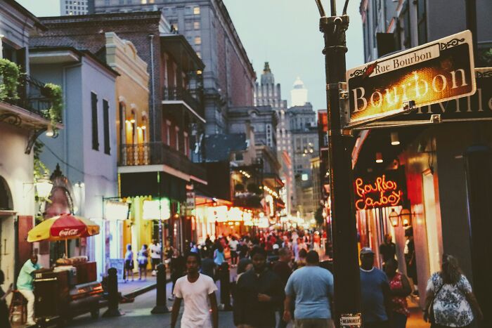 Crowded Bourbon Street at dusk with tourists exploring shops and cafes, showcasing a FOMO-induced experience.
