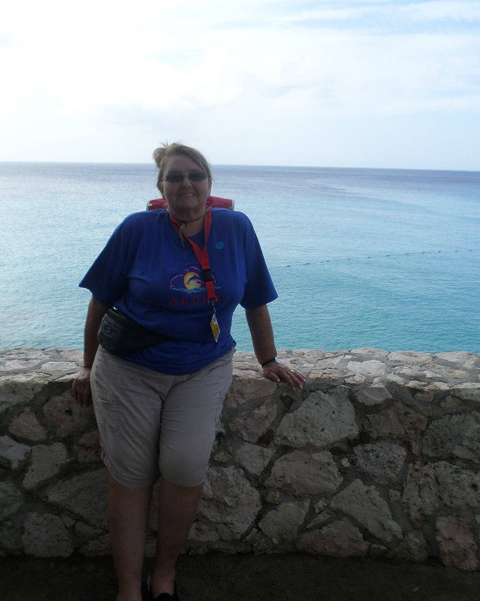 Woman standing by the ocean in a blue shirt and light shorts, connected to an old investigation. Woman standing by the ocean in a blue shirt and light shorts, connected to an old investigation.