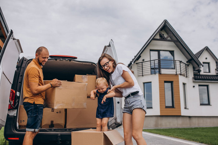 Family unpacking boxes from a van, moving to stepdad’s hometown for a better life, standing by a modern house. Family unpacking boxes from a van, moving to stepdad’s hometown for a better life, standing by a modern house.