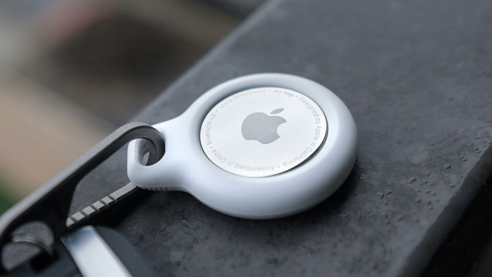 Apple AirTag attached to a keyring on a textured surface, symbolizing tracking and child safety concerns.