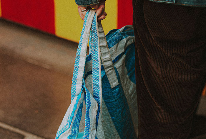 Person holding a blue-striped shopping bag, an example of moms getting shamed by strangers.