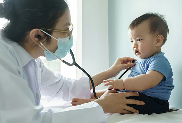 Doctor examines baby with stethoscope, illustrating a mom's experience of strangers shaming parenting choices.