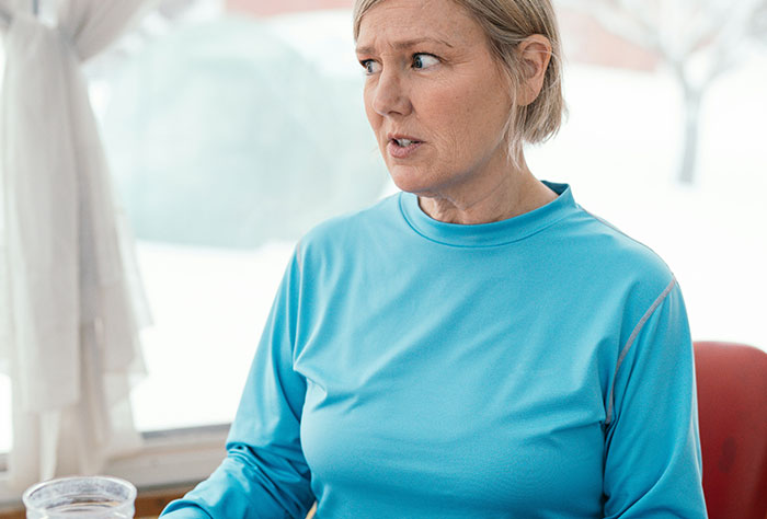 Woman in blue shirt looking surprised in a bright room, related to stories about moms shamed by strangers.