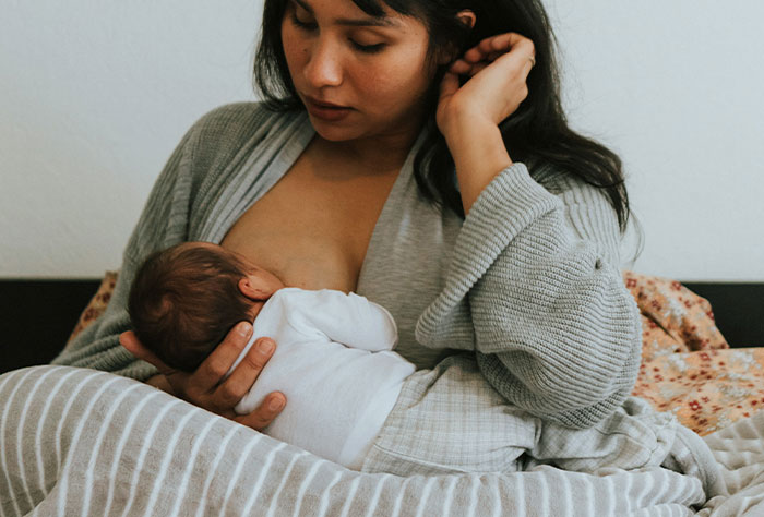Mom breastfeeding her baby, possibly facing judgment from strangers.