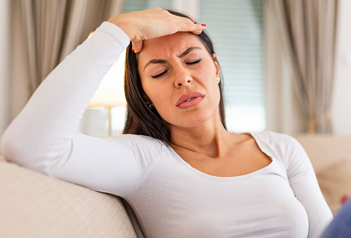 A mom looking stressed on a couch, representing feelings of shame from strangers.