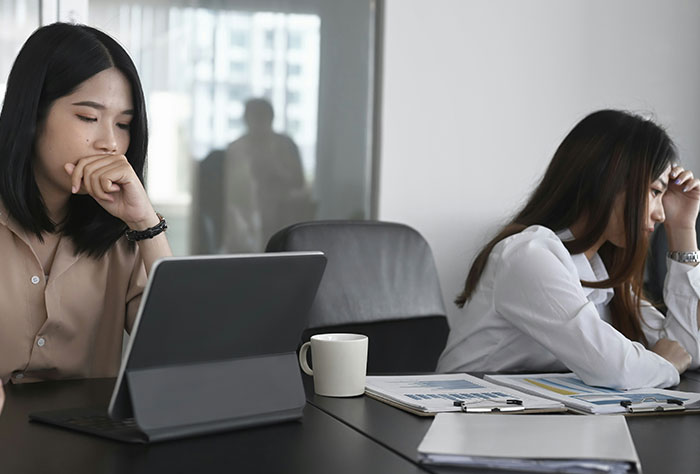 Two women looking stressed in an office setting, reflecting on experiences of being mom-shamed by strangers.