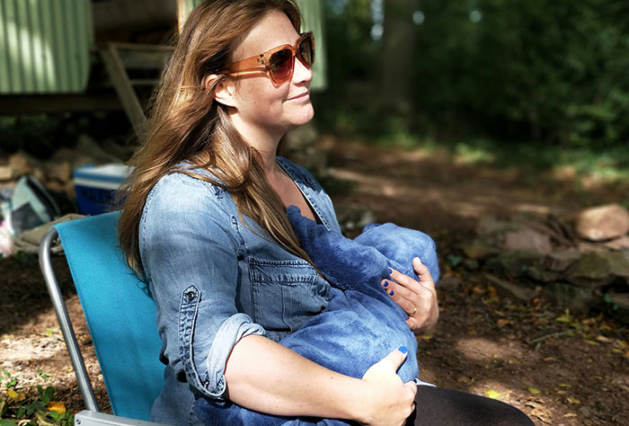 Mom enjoying a sunny day outside, wearing sunglasses and holding her baby, illustrating public motherhood experiences.