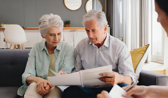 Elderly couple reviewing documents on a couch, discussing moral grounds related to an inheritance.