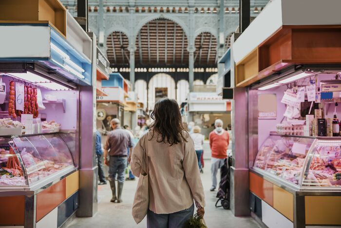 Person walks in a bustling market, surrounded by various food stalls, capturing cringiest moments among strangers.