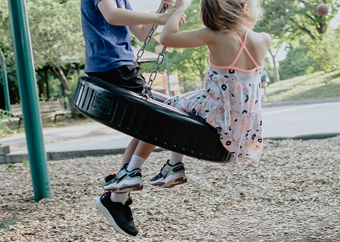 Children playing on a tire swing in a park on a sunny day.