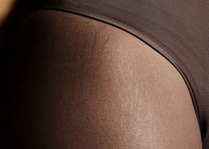 Close-up of a person's leg and hip wearing brown clothing, showcasing texture of the fabric.