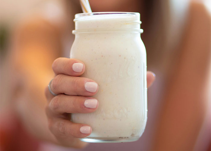 Person holding a mason jar filled with a creamy drink, showcasing family-related oddities.