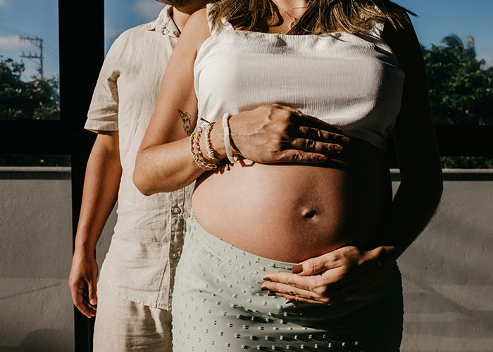 Pregnant woman with partner holding her belly, capturing a family moment.