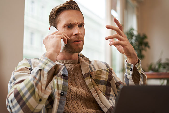 Man on a phone call looking frustrated, wearing a plaid shirt, gesturing with his hand. Man on a phone call looking frustrated, wearing a plaid shirt, gesturing with his hand.