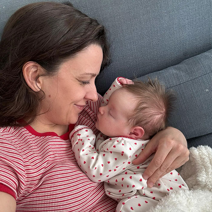 Ms. Rachel cuddling a baby on a couch, highlighting Ms. Rachel&rsquo;s net worth rise story.
