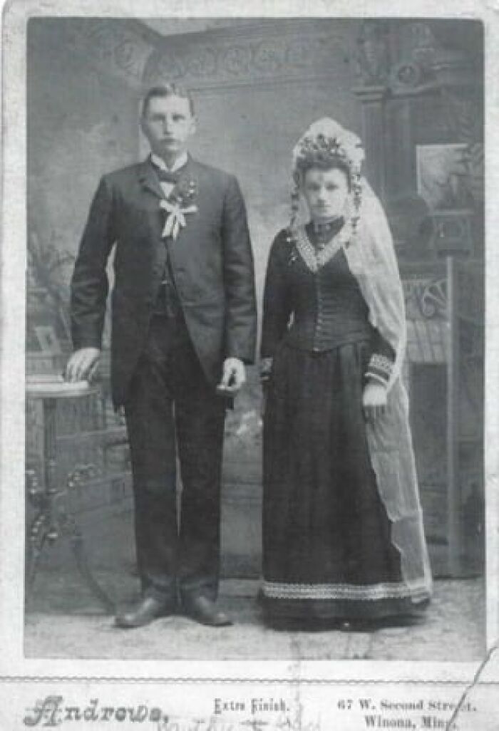 Vintage wedding photo of a couple in formal attire, with intricate lace details on the bride's headpiece and dress.