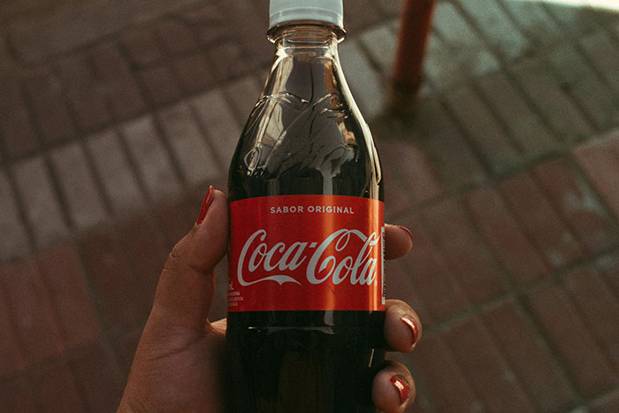 Hand holding a Coca-Cola bottle, illustrating product marketing strategies.