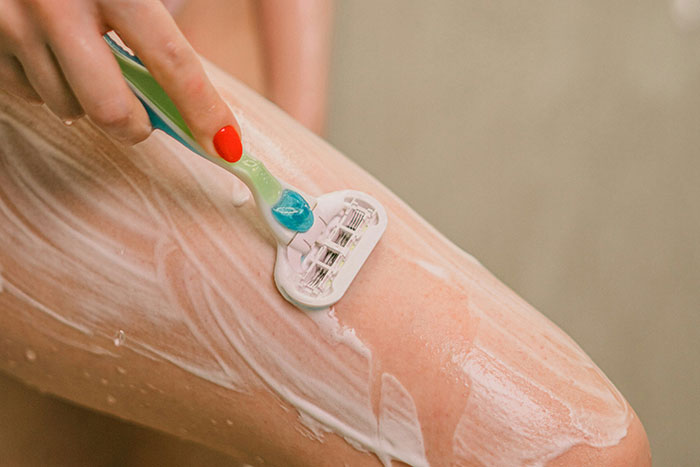 Person shaving leg with razor, highlighting product-related lies in marketing.
