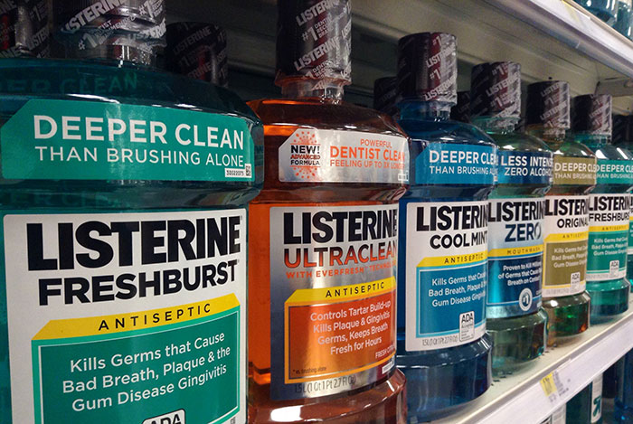 Listerine bottles on a store shelf, showcasing claims of deeper clean compared to brushing.