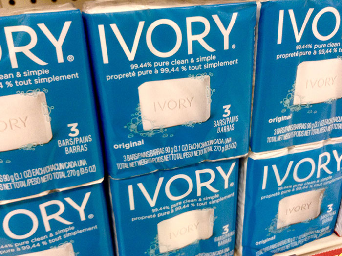 Ivory soap packaging claiming 99.44% purity stacked on a store shelf.