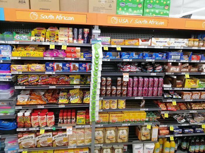 American food section in a store, featuring snacks and beverages, alongside South African products on shared shelves.