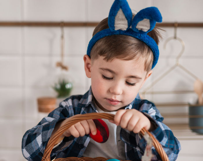 Child with bunny ears explores an Easter basket.
