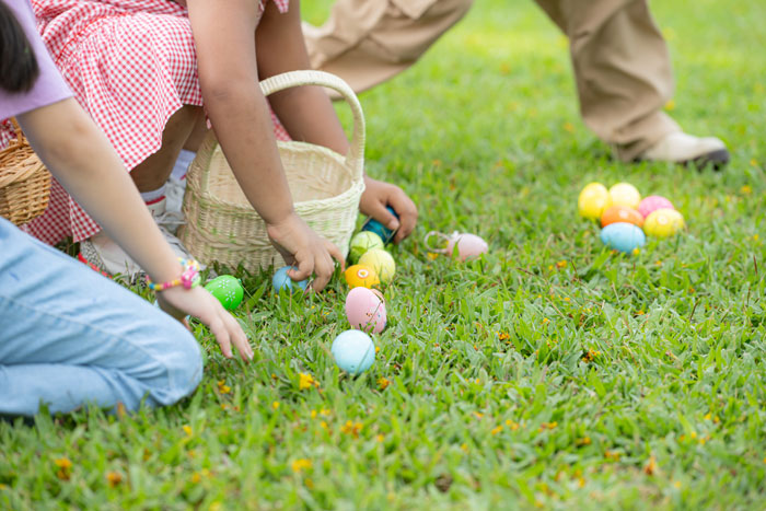 Children gathering Easter eggs on grass, with colorful baskets.