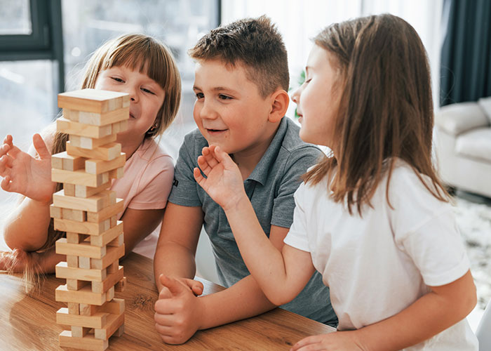 Children playing with wooden blocks indoors, focused and engaged.
