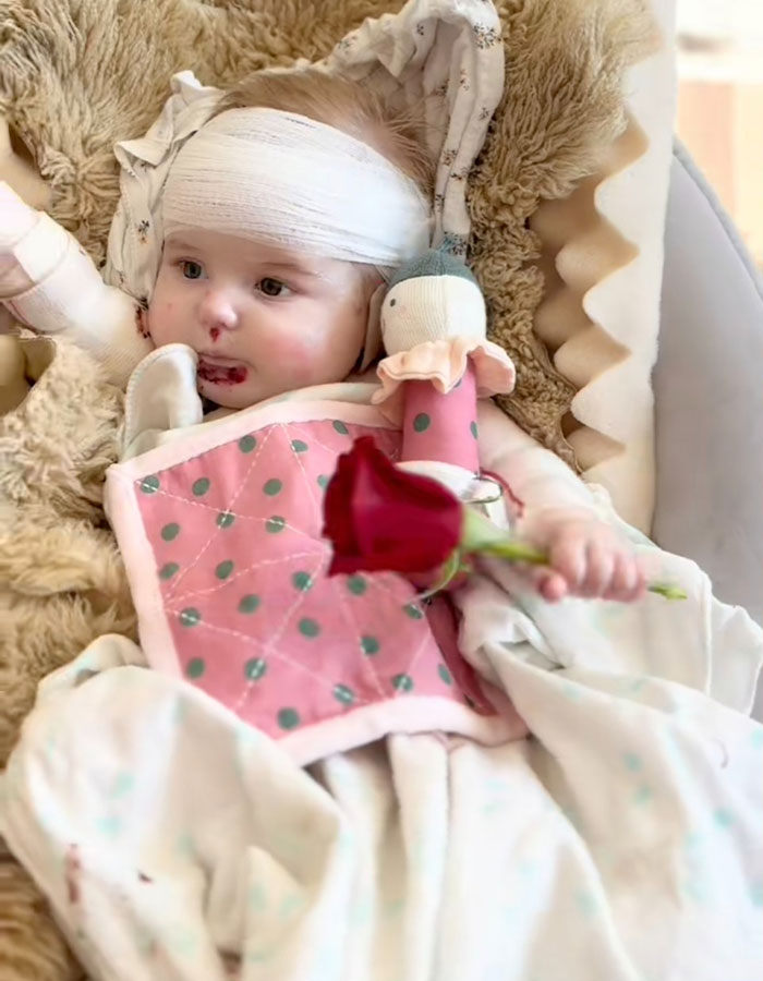 Baby with bandage and rose in crib, representing influencer's daughter's heartbreaking passing at 10 months.