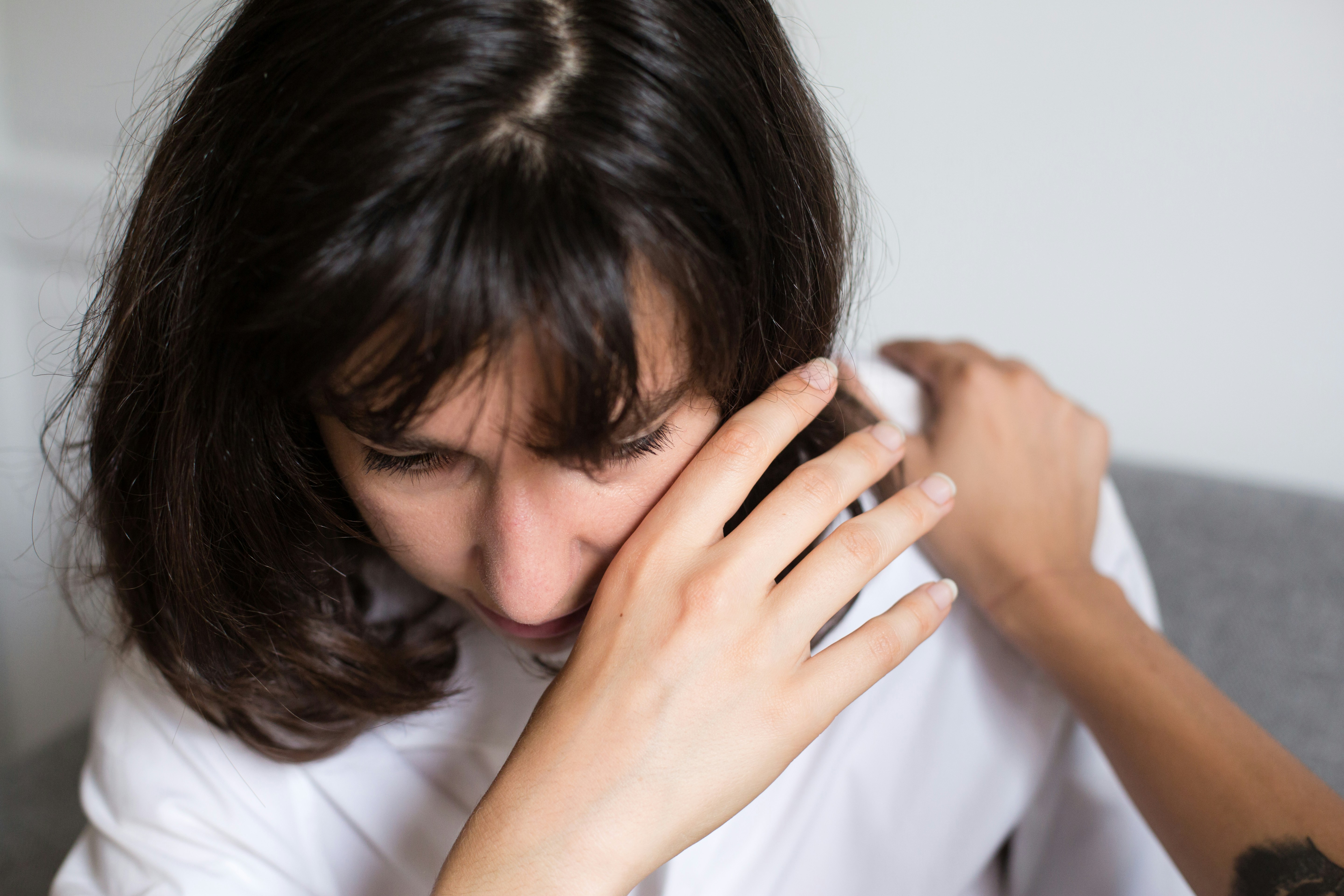 A woman in distress is consoled by another person's hand on her shoulder during a chaotic family event.