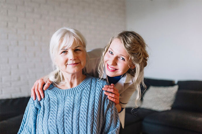 Woman smiling next to seated elderly woman, highlighting family bonds after a relationship conflict.