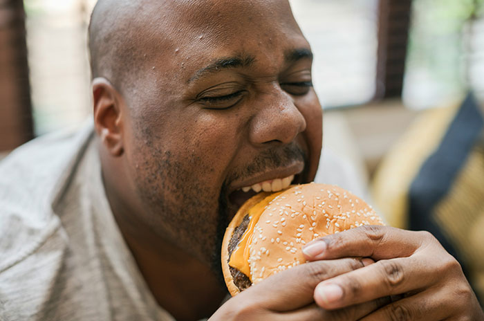 Man enjoying a cheeseburger, illustrating nuances of US culture that non-Americans discover while traveling.